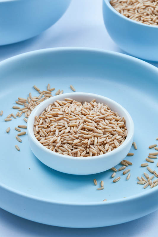 白色纸背景上的青釉瓷餐具及木质餐具装的燕麦米图片