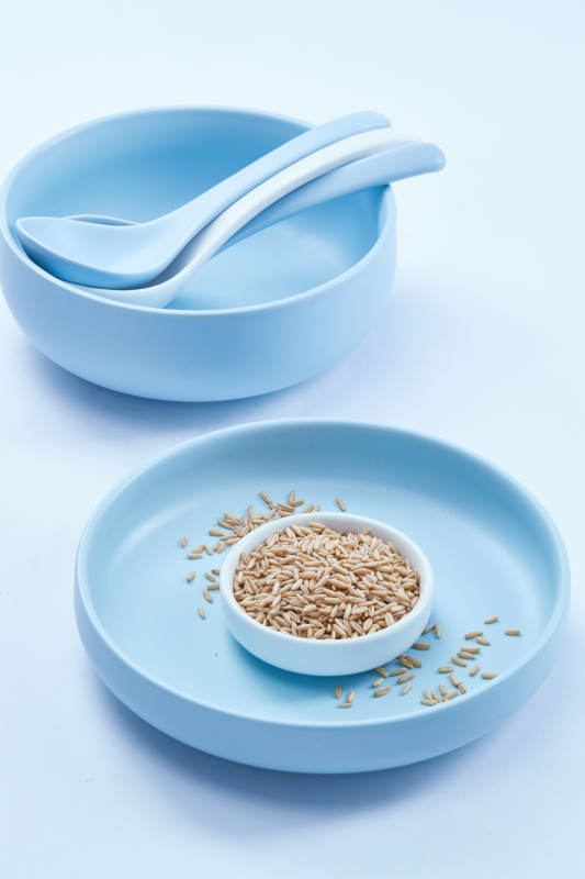 白色纸背景上的青釉瓷餐具及木质餐具装的燕麦米图片