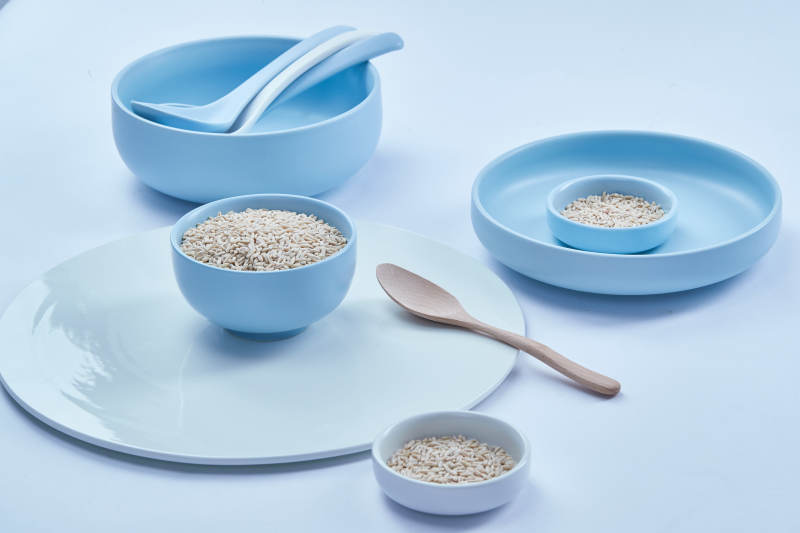 白色纸背景上的青釉瓷餐具及木质餐具装的燕麦米图片