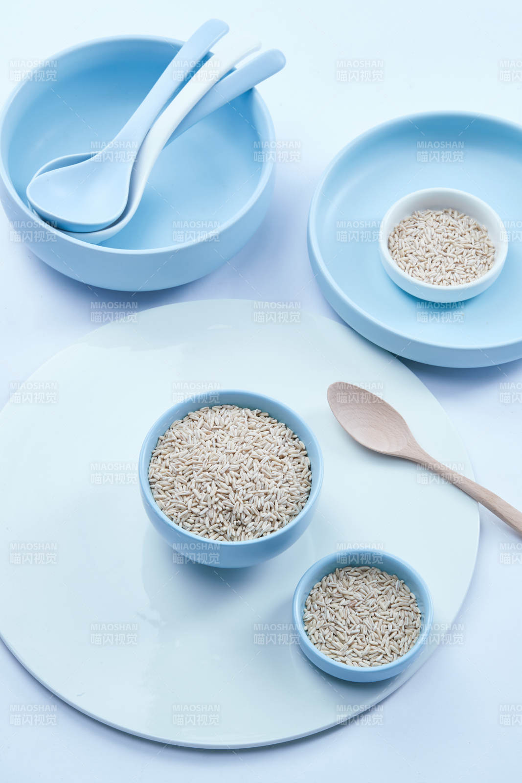 白色纸背景上的青釉瓷餐具及木质餐具装的燕麦米图片