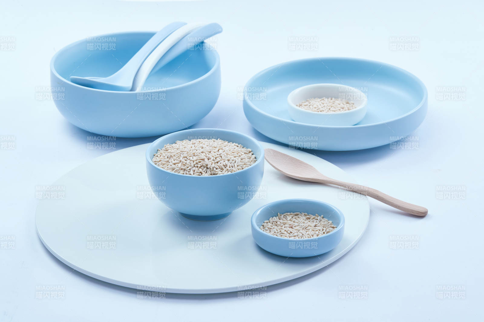 白色纸背景上的青釉瓷餐具及木质餐具装的燕麦米图片