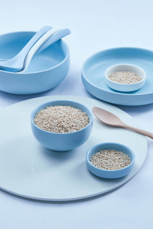 白色纸背景上的青釉瓷餐具及木质餐具装的燕麦米图片