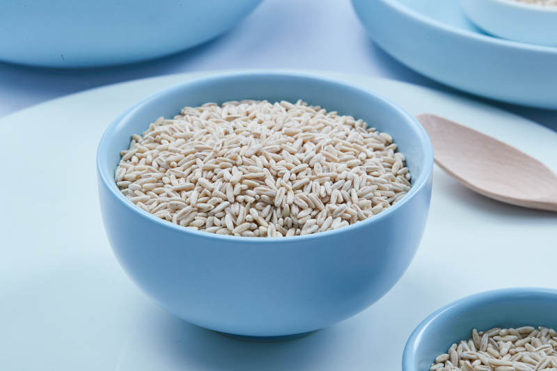 白色纸背景上的青釉瓷餐具及木质餐具装的燕麦米图片