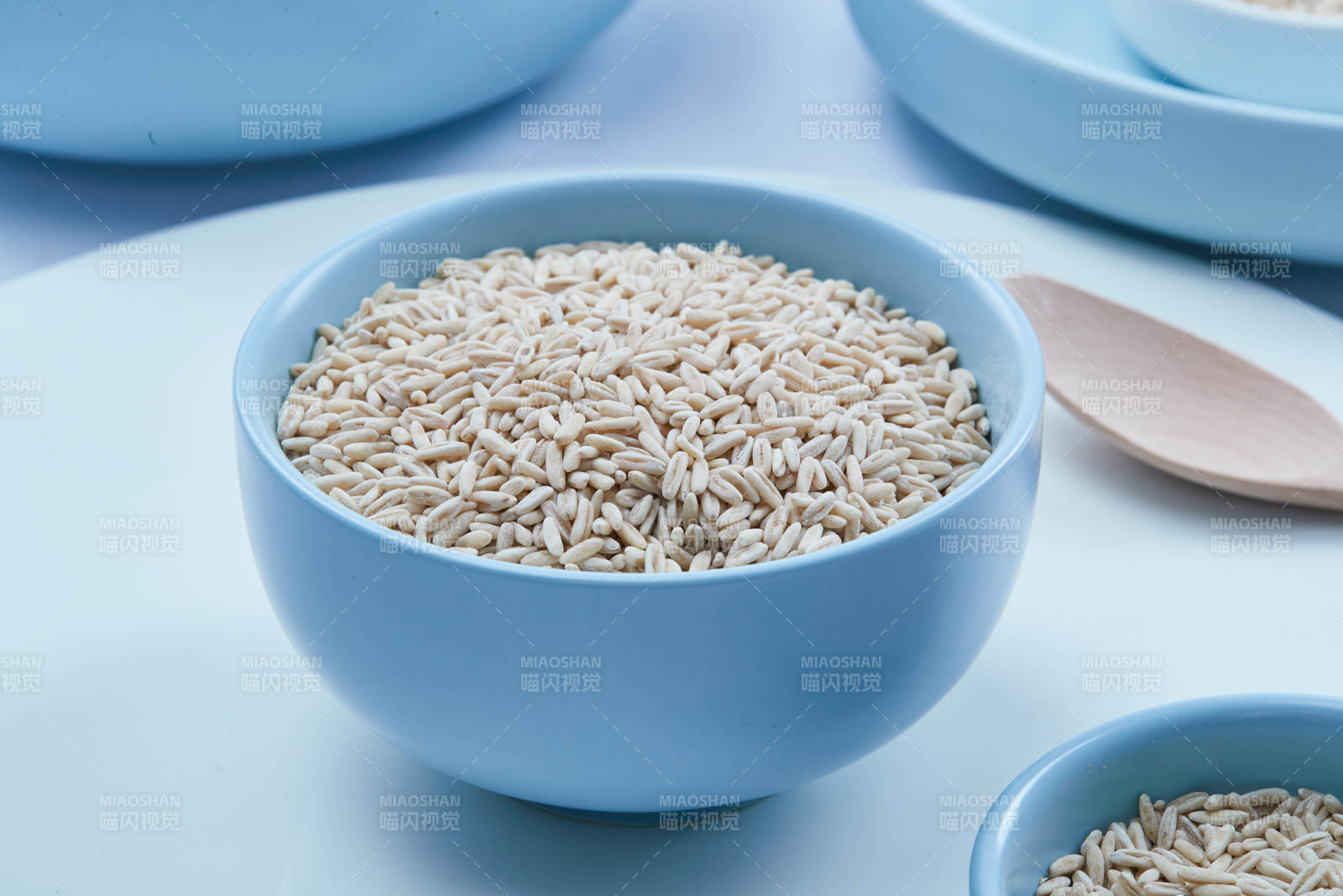 白色纸背景上的青釉瓷餐具及木质餐具装的燕麦米图片