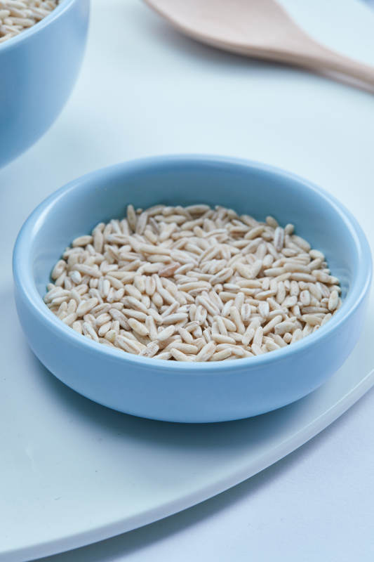 白色纸背景上的青釉瓷餐具及木质餐具装的燕麦米图片