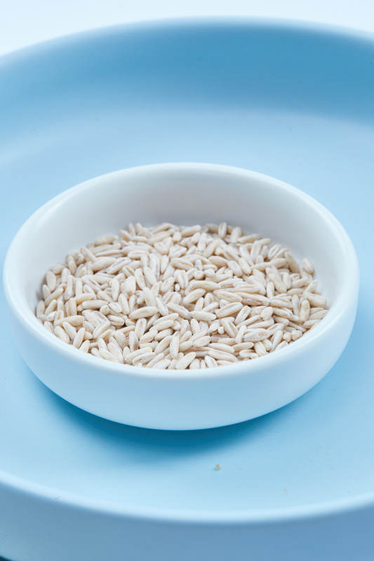 白色纸背景上的青釉瓷餐具及木质餐具装的燕麦米图片