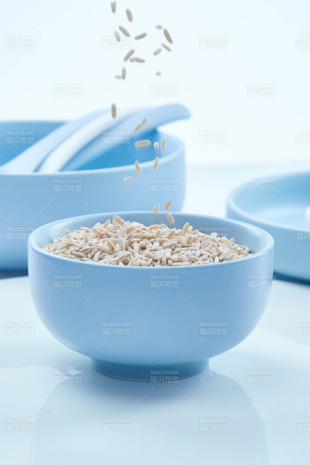 白色纸背景上的青釉瓷餐具及木质餐具装的燕麦米图片