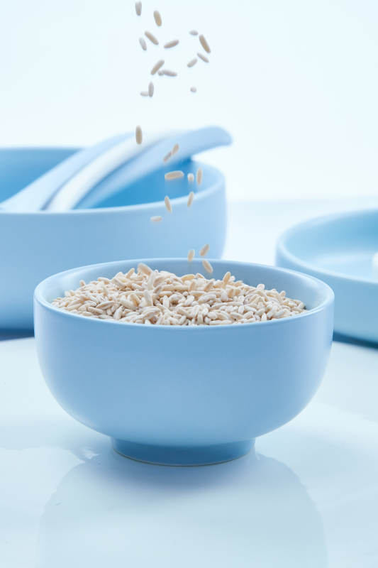 白色纸背景上的青釉瓷餐具及木质餐具装的燕麦米图片