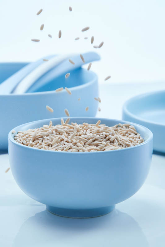 白色纸背景上的青釉瓷餐具及木质餐具装的燕麦米图片