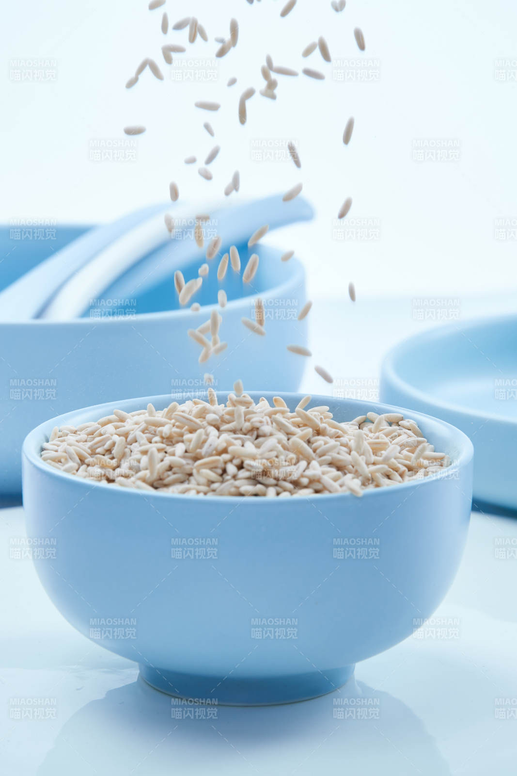 白色纸背景上的青釉瓷餐具及木质餐具装的燕麦米图片