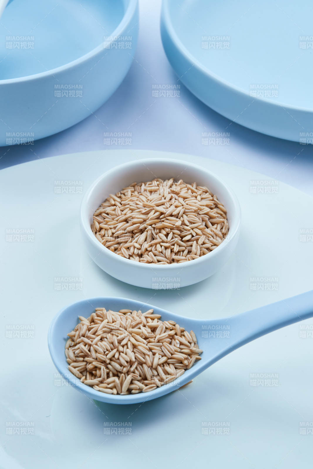 白色纸背景上的青釉瓷餐具及木质餐具装的燕麦米图片