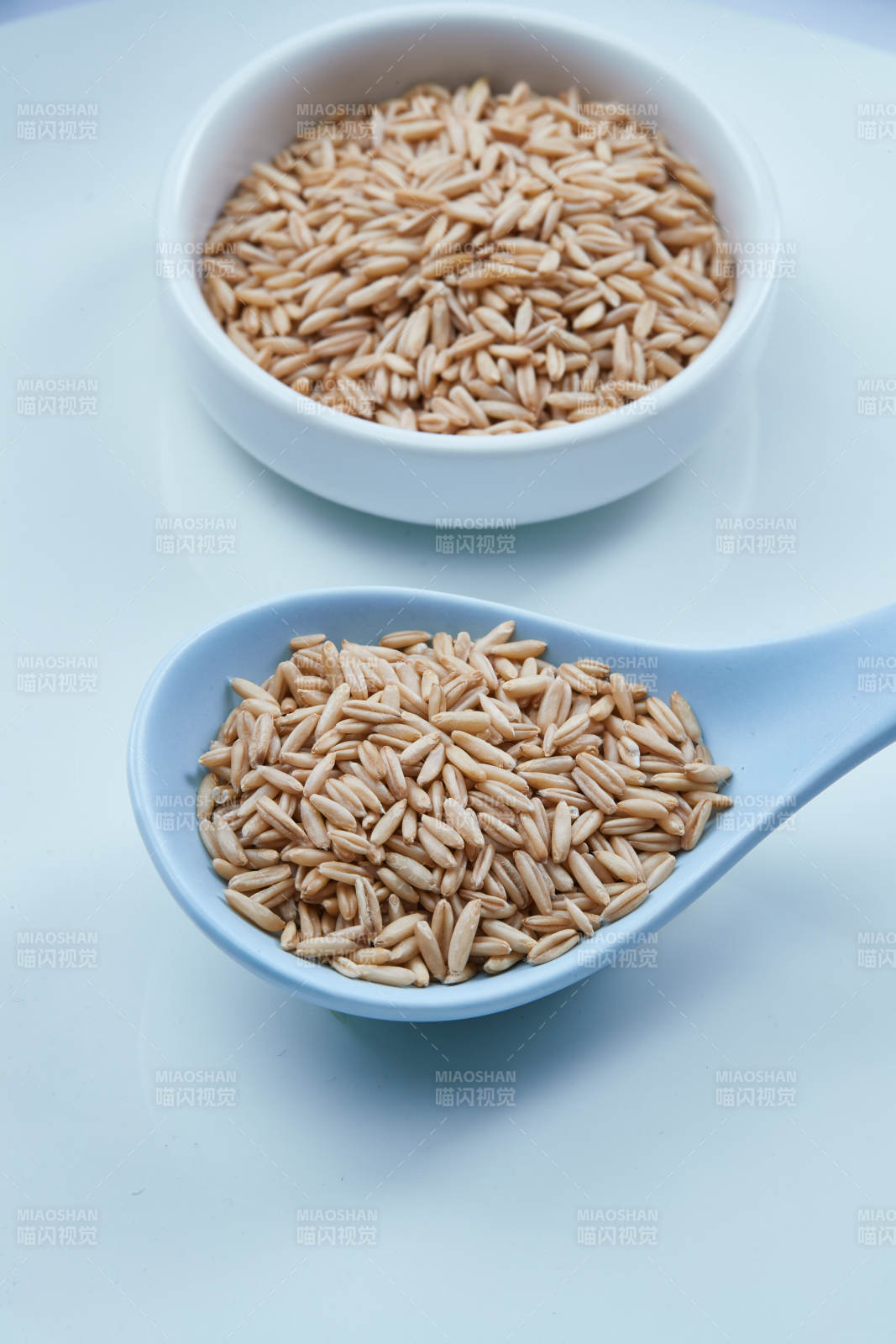 白色纸背景上的青釉瓷餐具及木质餐具装的燕麦米图片