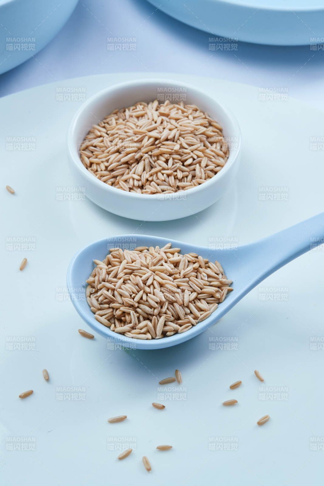 白色纸背景上的青釉瓷餐具及木质餐具装的燕麦米图片