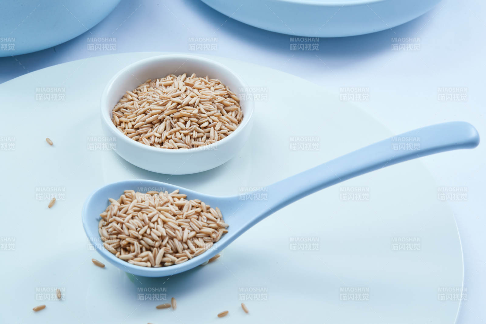 白色纸背景上的青釉瓷餐具及木质餐具装的燕麦米图片