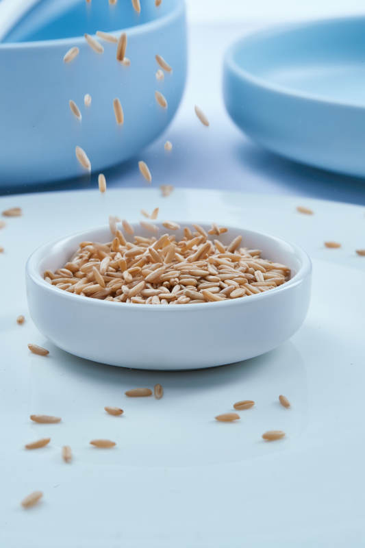 白色纸背景上的青釉瓷餐具及木质餐具装的燕麦米图片