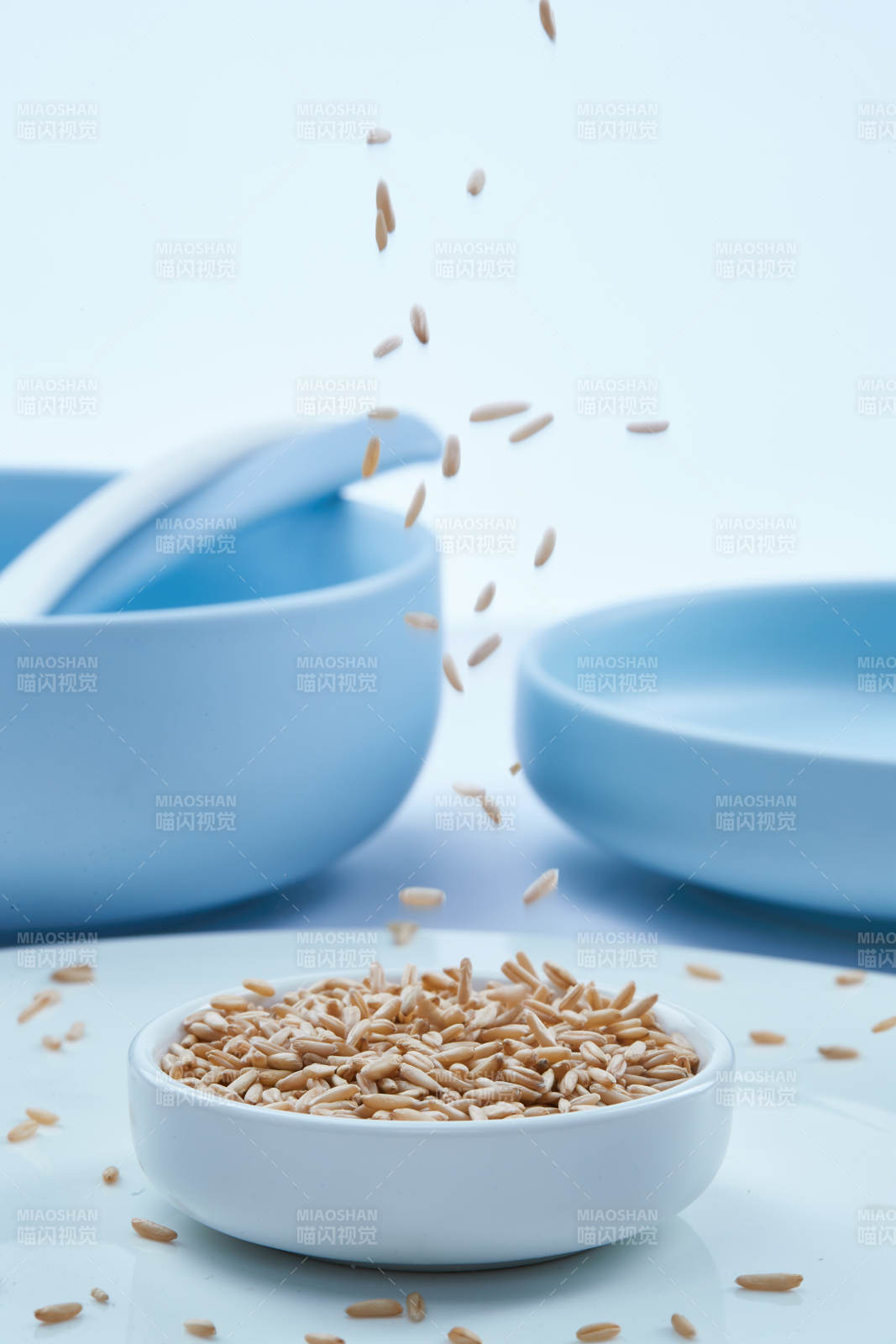 白色纸背景上的青釉瓷餐具及木质餐具装的燕麦米图片