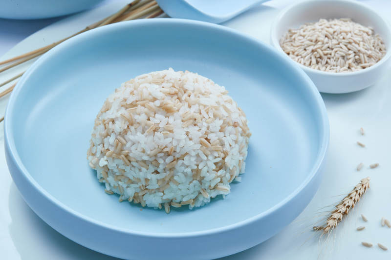 白色纸背景上的青釉瓷餐具及木质餐具装的燕麦米图片