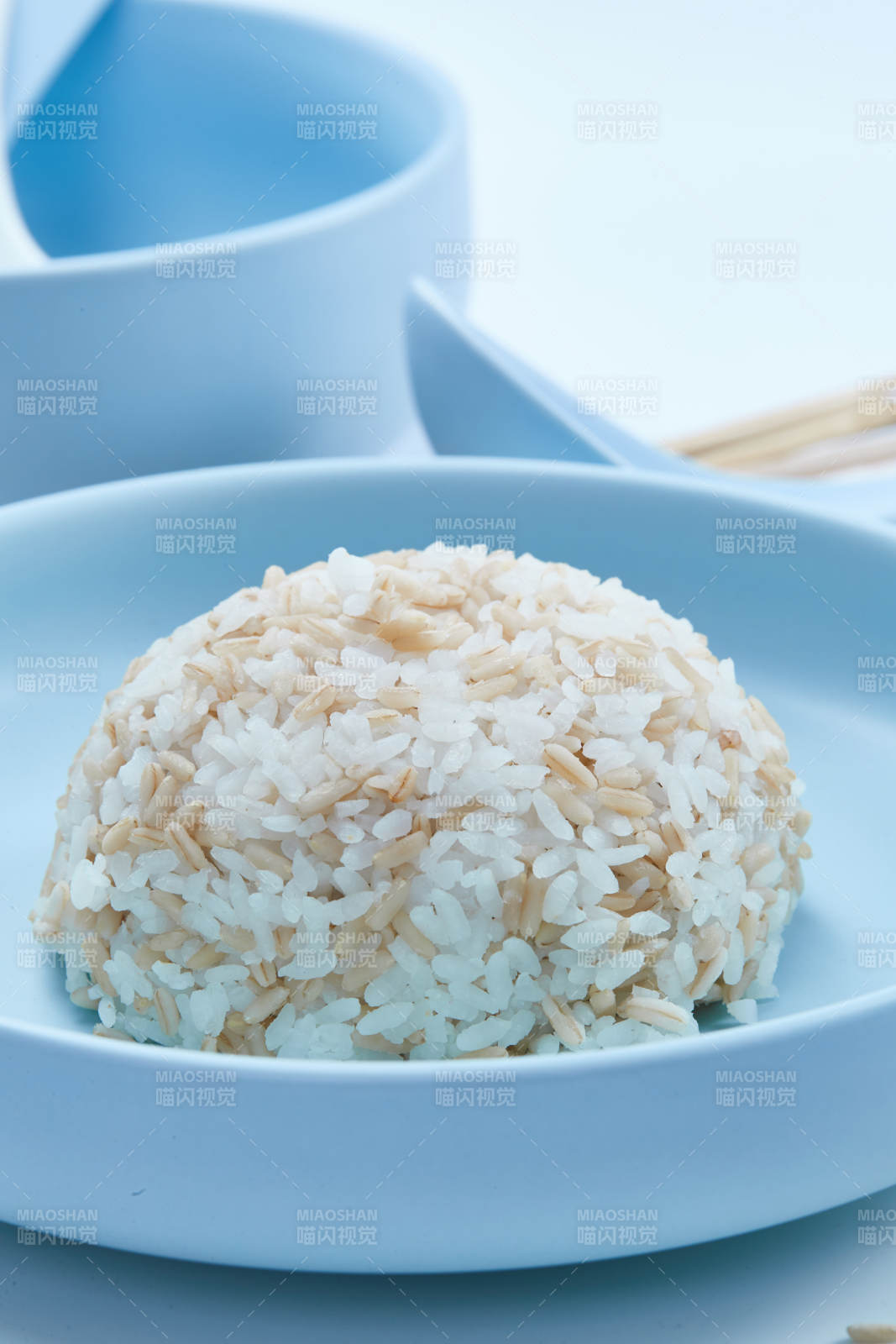 白色纸背景上的青釉瓷餐具及木质餐具装的燕麦米图片