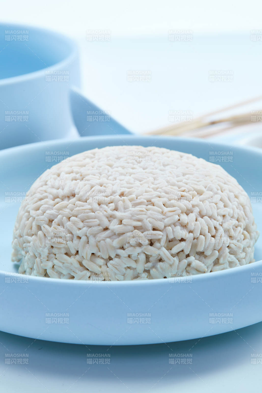 白色纸背景上的青釉瓷餐具及木质餐具装的燕麦米图片