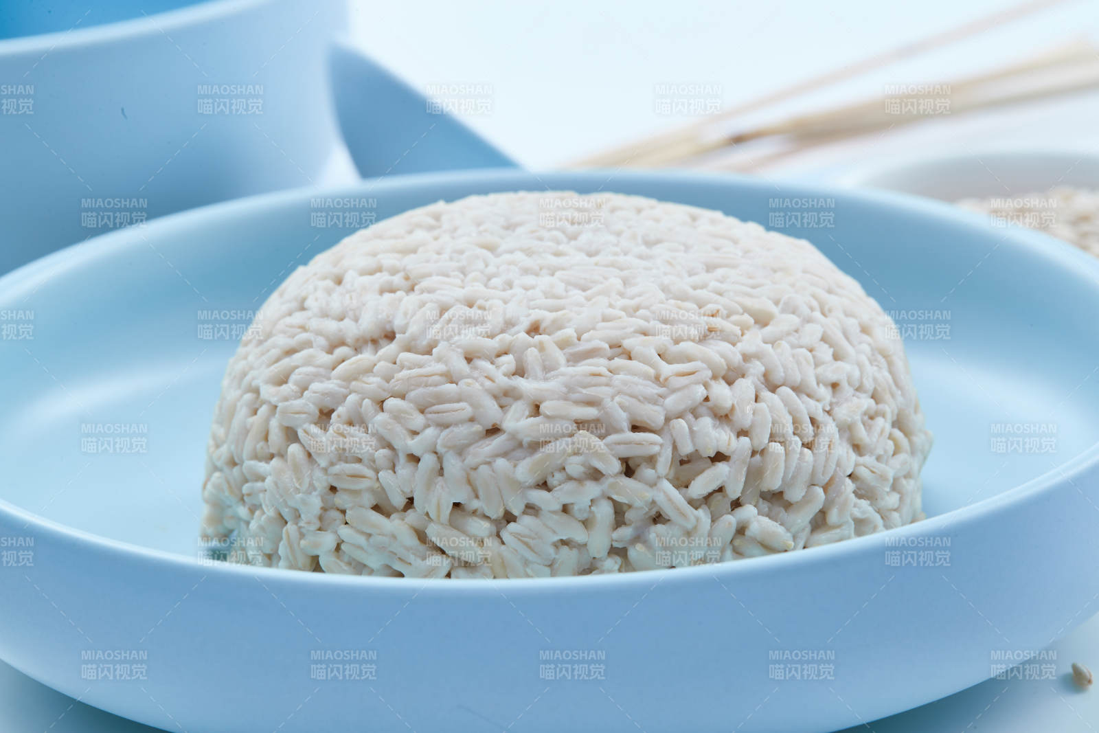 白色纸背景上的青釉瓷餐具及木质餐具装的燕麦米图片