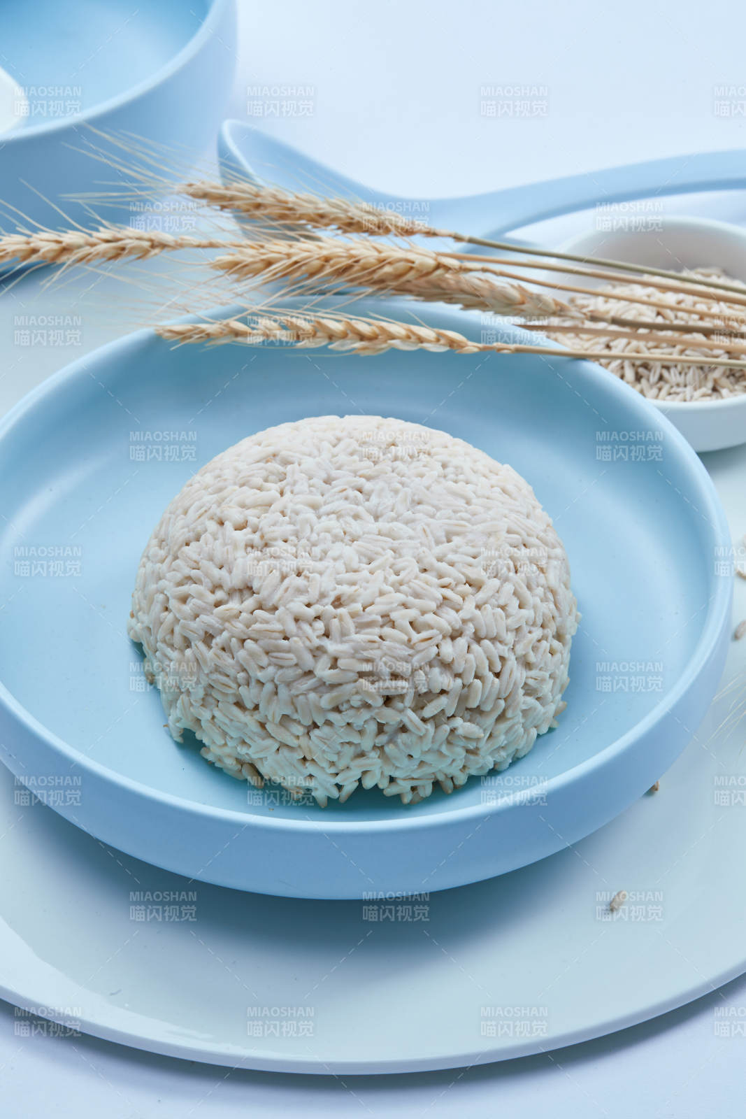 白色纸背景上的青釉瓷餐具及木质餐具装的燕麦米图片