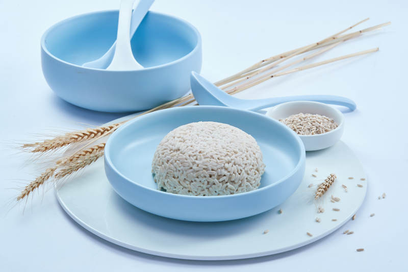 白色纸背景上的青釉瓷餐具及木质餐具装的燕麦米图片