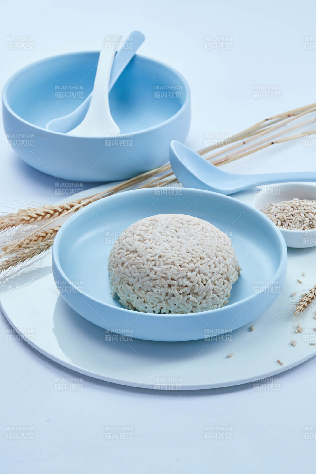 白色纸背景上的青釉瓷餐具及木质餐具装的燕麦米图片