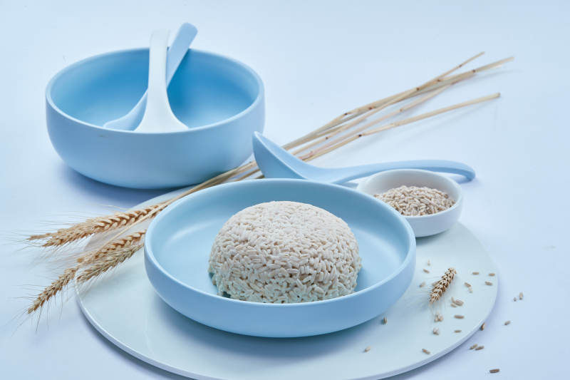 白色纸背景上的青釉瓷餐具及木质餐具装的燕麦米图片