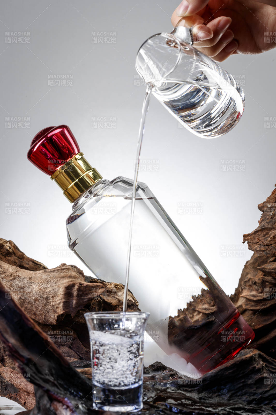 向木板上摆放的酒具内倒入清澈的白酒激起无数酒花图片