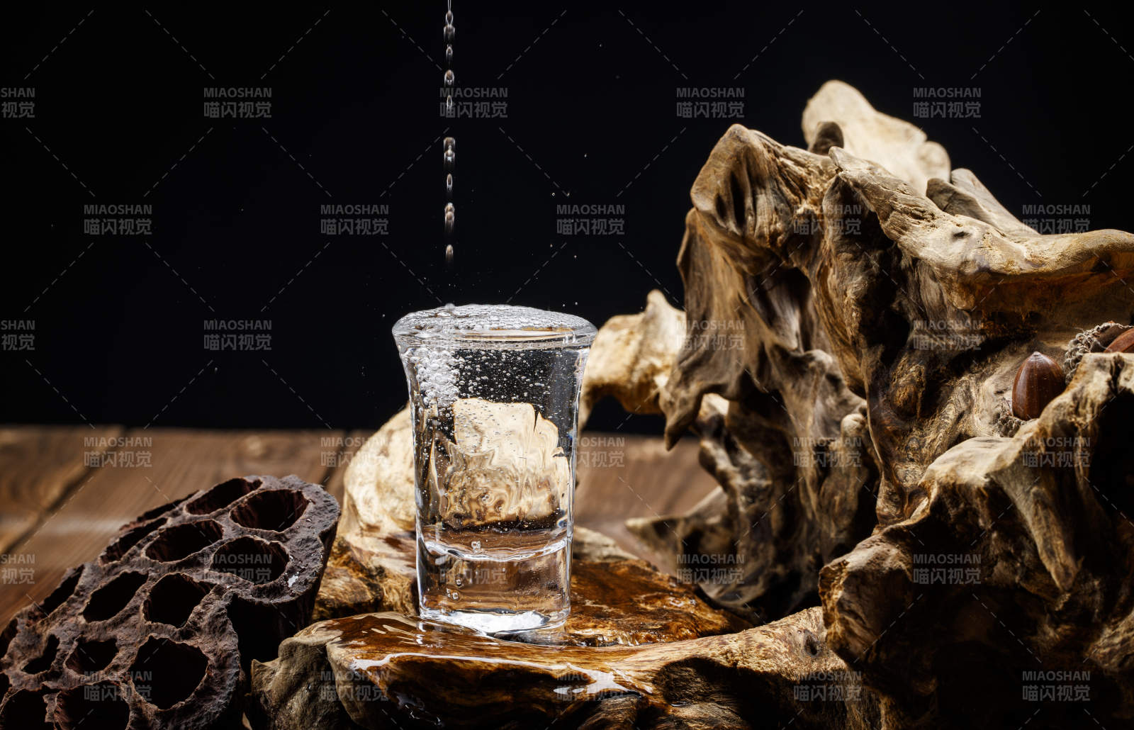 向木板上摆放的酒具内倒入清澈的白酒激起无数酒花图片