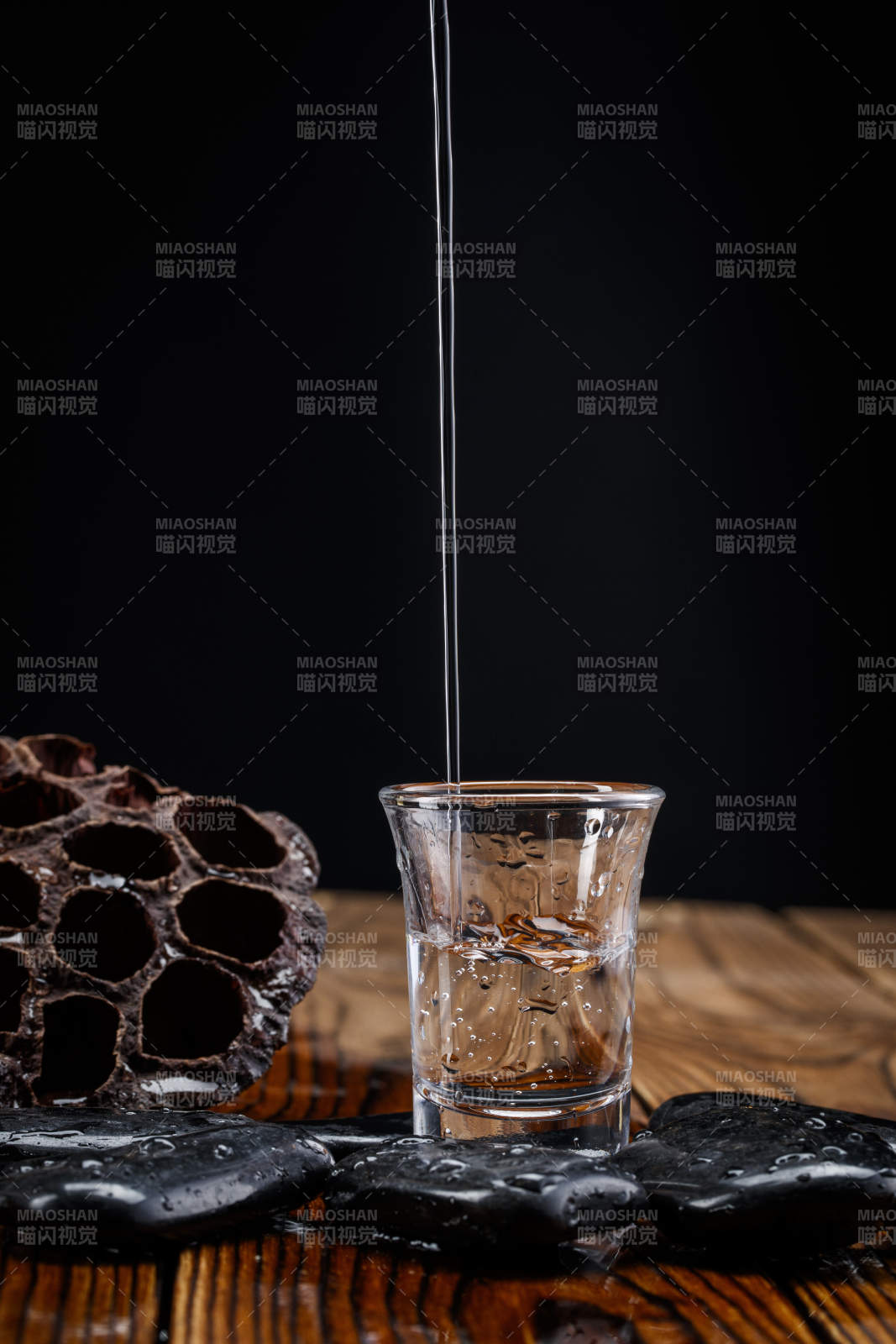 向木板上摆放的酒具内倒入清澈的白酒激起无数酒花图片