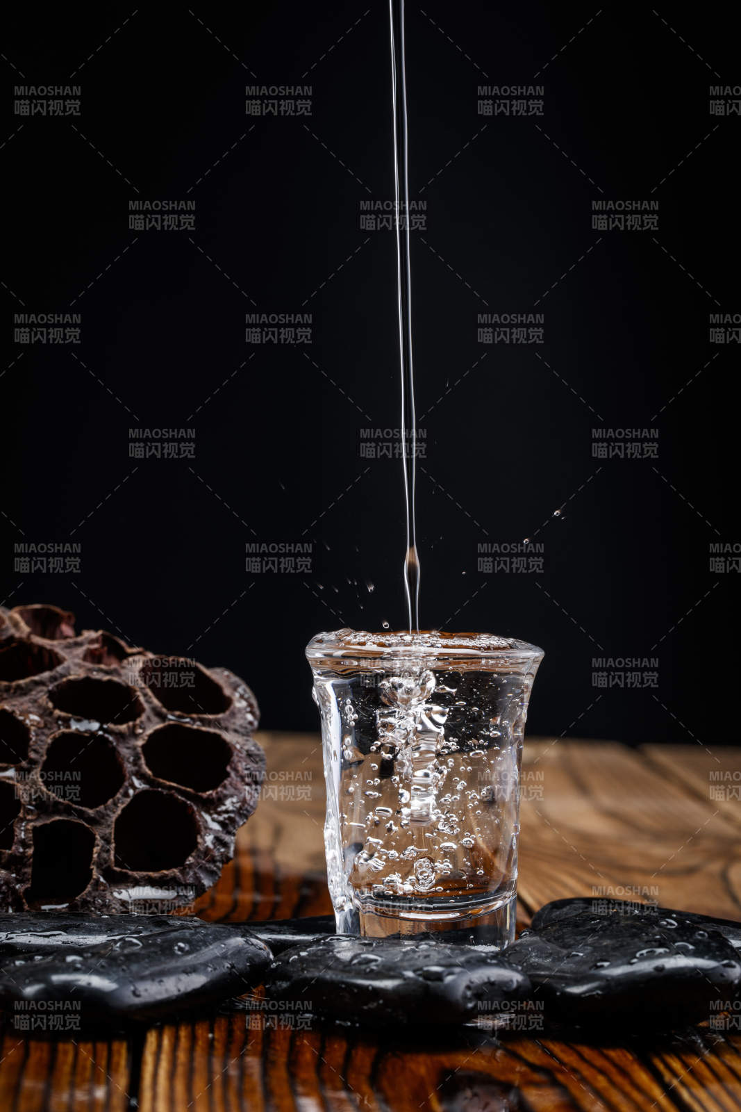 向木板上摆放的酒具内倒入清澈的白酒激起无数酒花图片