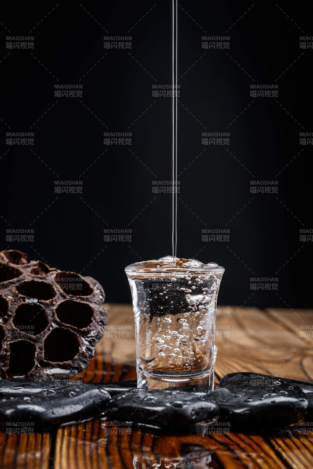 向木板上摆放的酒具内倒入清澈的白酒激起无数酒花图片