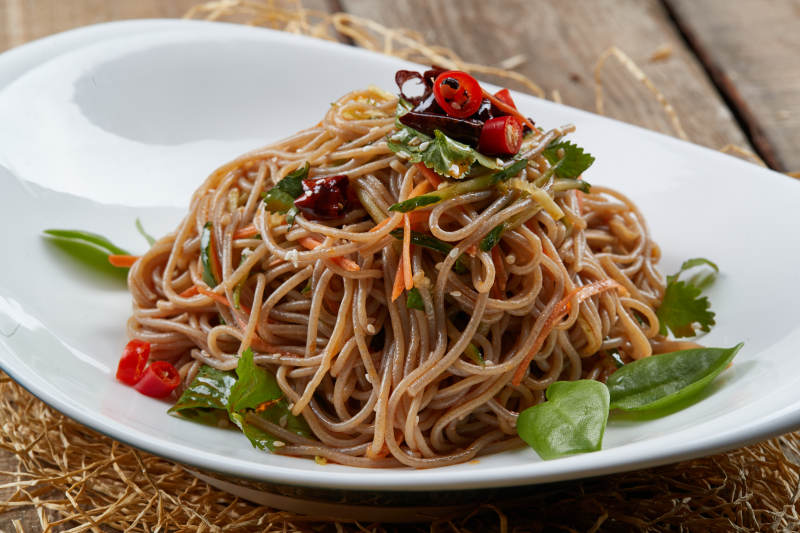 白色瓷盘装的的香辣荞麦凉面图片