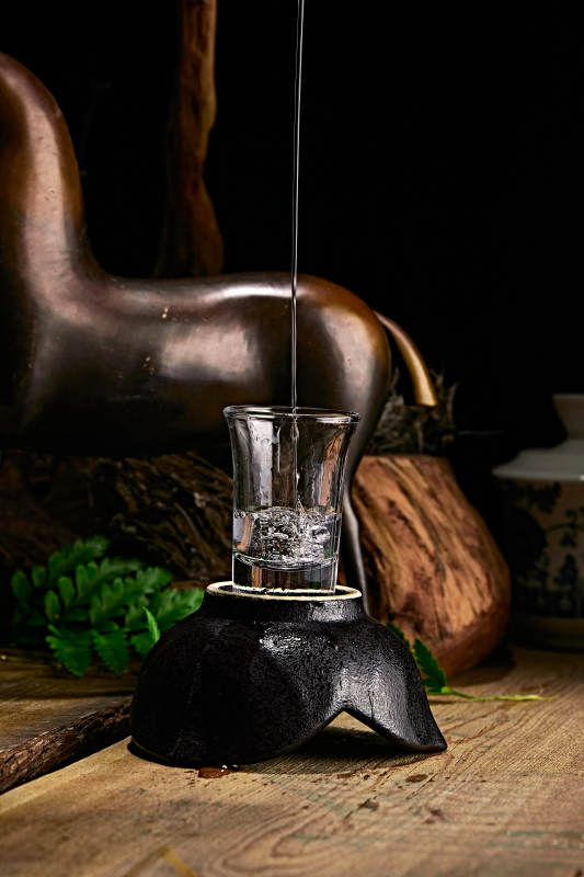 木板上摆放的酒具倒入清澈的白酒激起酒花图片