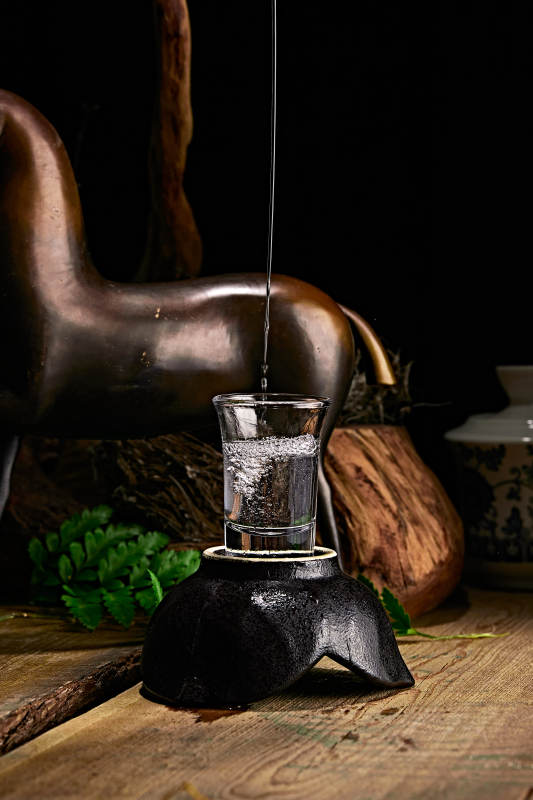 木板上摆放的酒具倒入清澈的白酒激起酒花图片