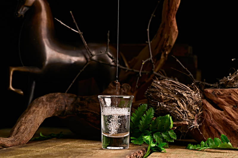 木板上摆放的酒具倒入清澈的白酒激起酒花图片