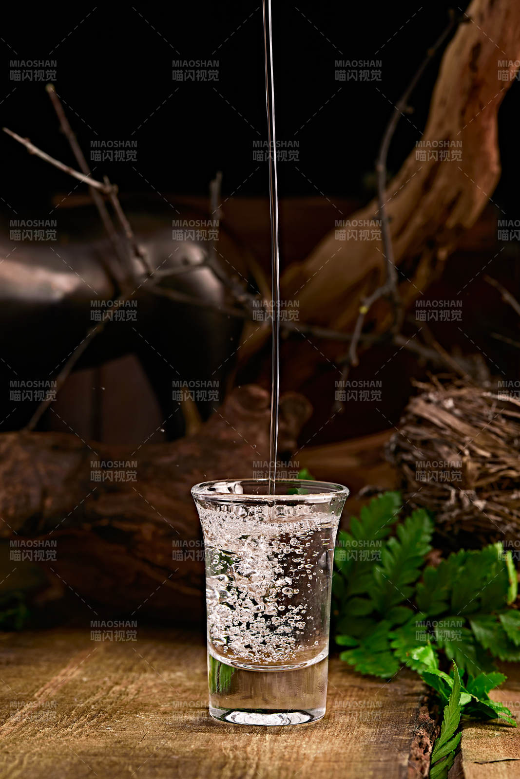 木板上摆放的酒具倒入清澈的白酒激起酒花图片