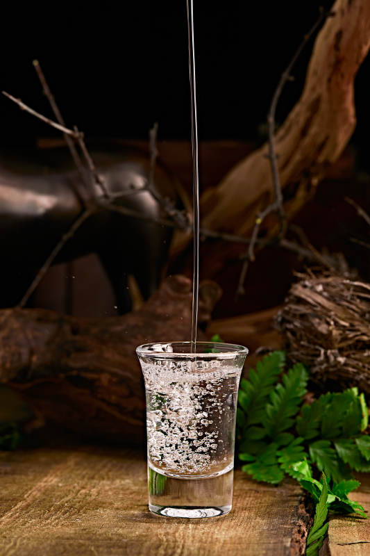 木板上摆放的酒具倒入清澈的白酒激起酒花图片