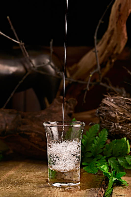 木板上摆放的酒具倒入清澈的白酒激起酒花图片