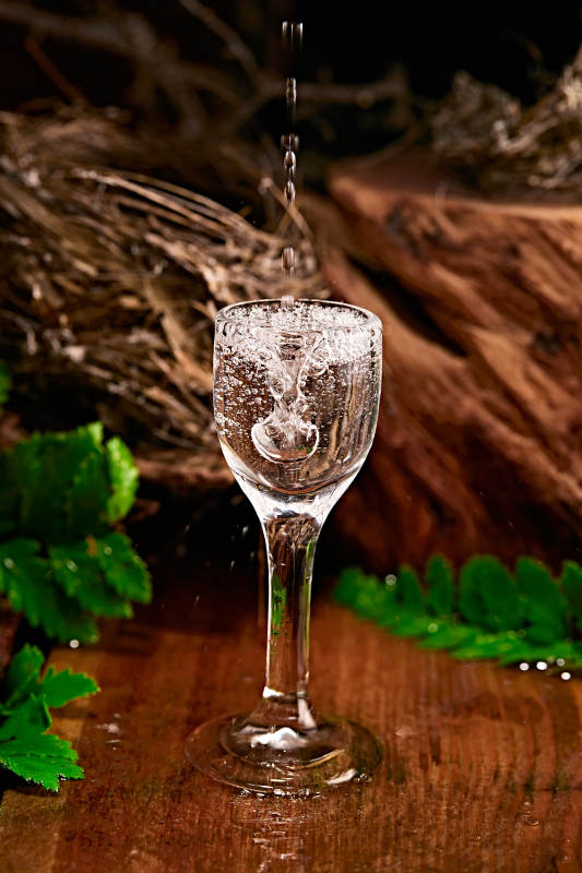 木板上摆放的酒具倒入清澈的白酒激起酒花图片