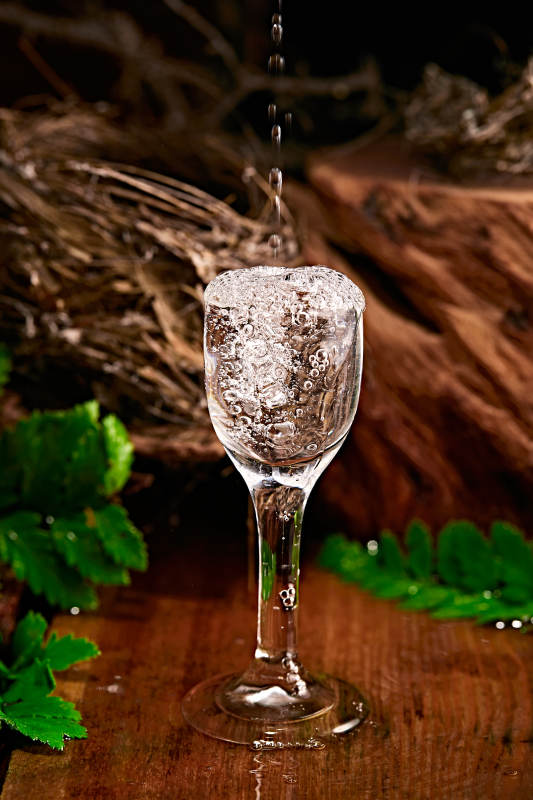 木板上摆放的酒具倒入清澈的白酒激起酒花图片