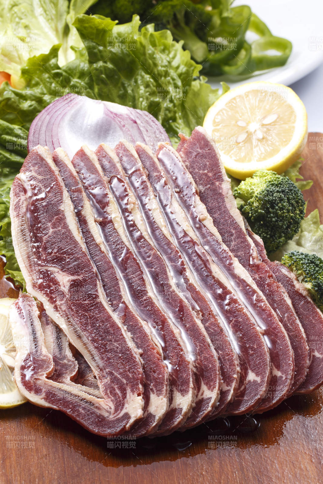 搭配柠檬洋葱生菜的牛肋排摆放在木质砧板上图片