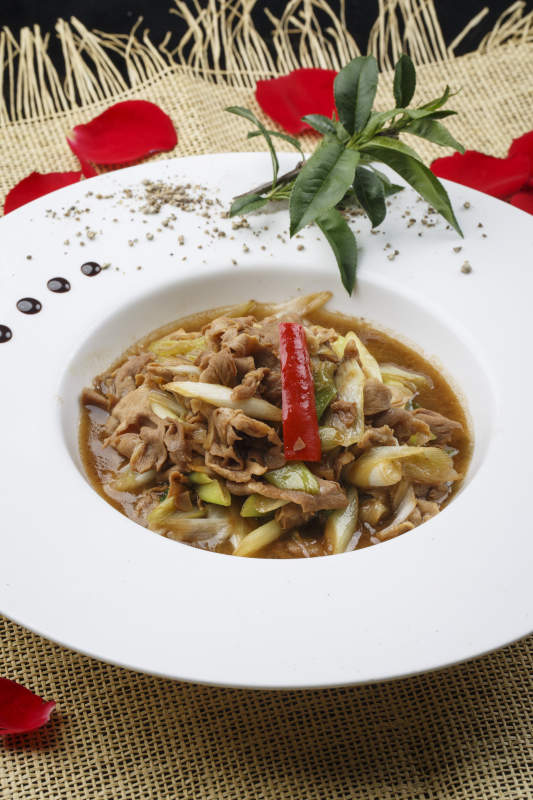 白色圆形瓷盘装的大葱爆羊肉图片