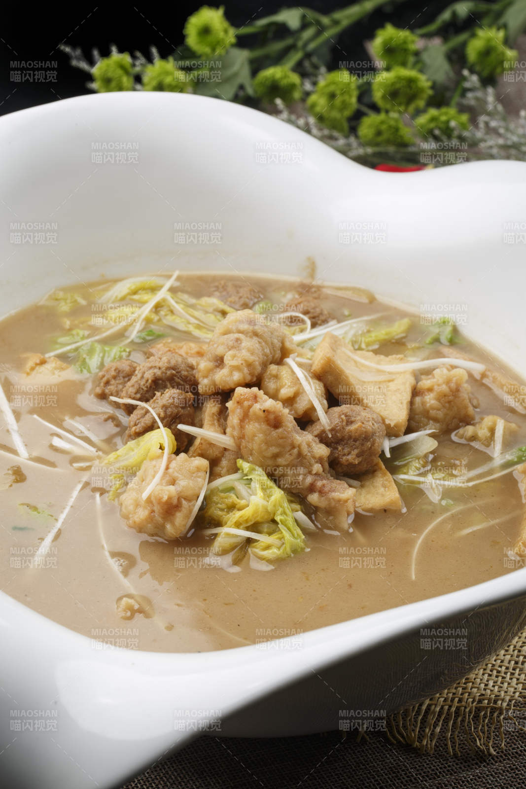 心形白色瓷汤盆装的酥肉卤豆泡图片