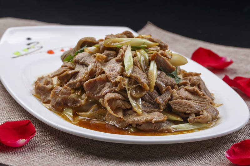 白色瓷盘装的大葱烧羊肉图片