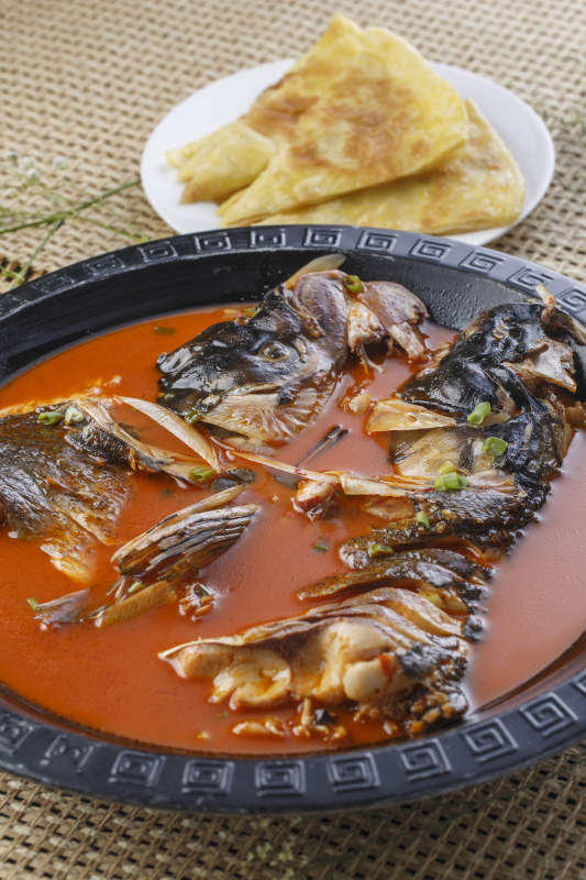 黑色铁盘装的浓汤鱼头泡大饼图片
