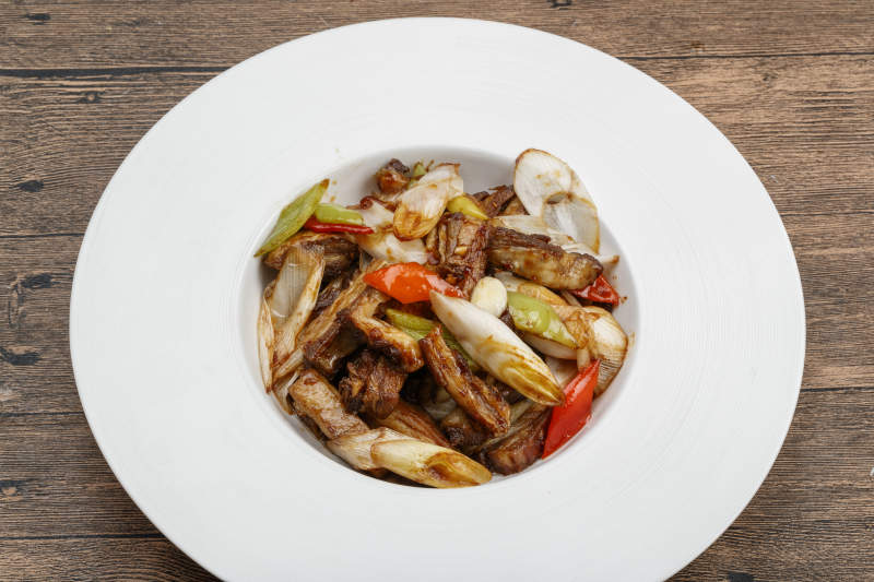 白色瓷盘装的葱爆羊五花肉图片