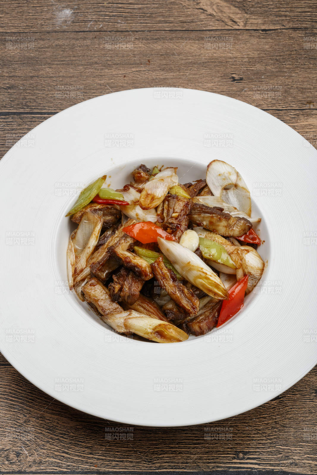 白色瓷盘装的葱爆羊五花肉图片