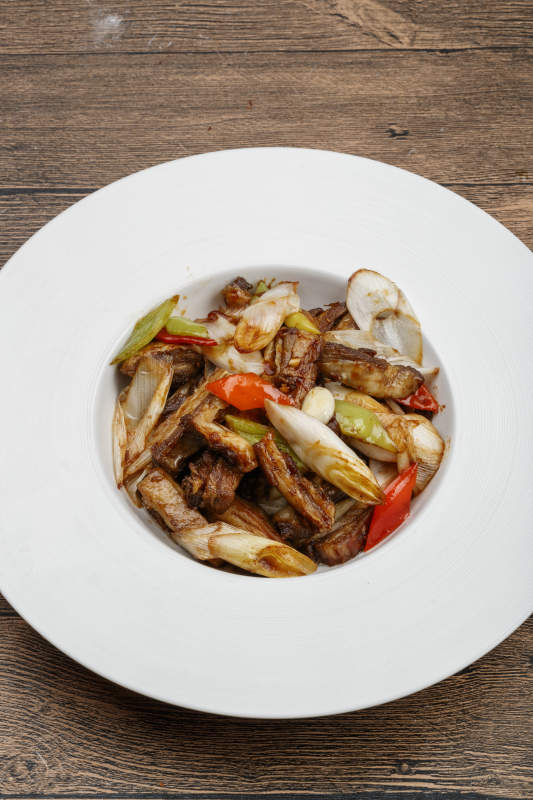 白色瓷盘装的葱爆羊五花肉图片